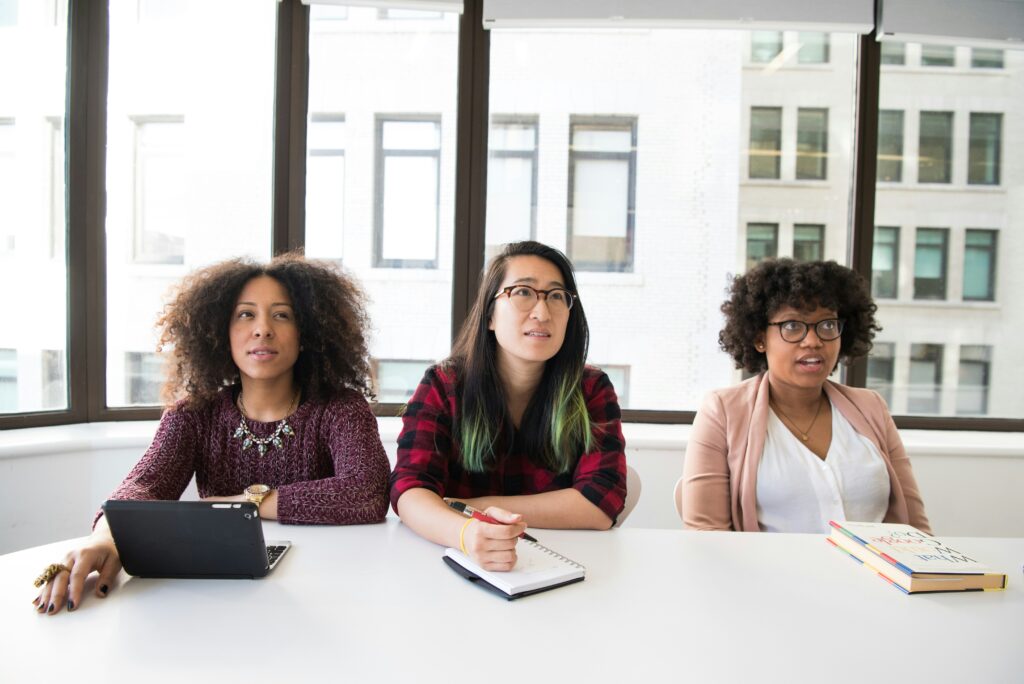 A team of 3 women sit around a table asking tough questions to overcome employee relations issues.